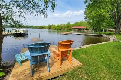 two chairs sitting on a dock next to a lake at Waterfront Cottage - Fireplace - Kawartha in Lakefield