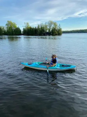 a woman is rowing a blue kayak on a lake at Waterfront Cottage - Fireplace - Kawartha in Lakefield