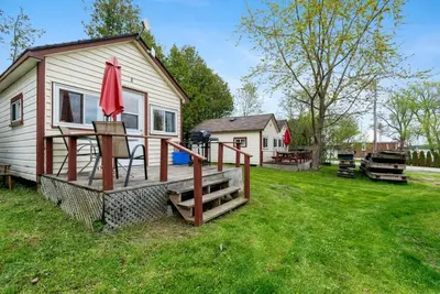 a tiny house with a deck and a red umbrella at Enjoy Relax at Rice Lakes in Bailieboro