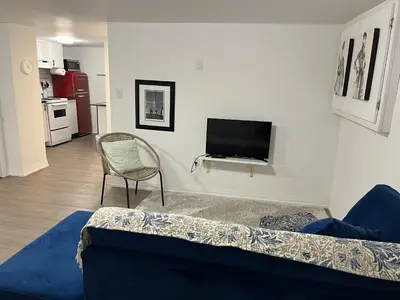 a living room with a couch and a tv on a wall at Merritt Place Niagara in St. Catharines