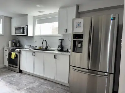 a kitchen with white cabinets and a stainless steel refrigerator at Entire 2 Bedroom Apartment in Kitchener in Kitchener