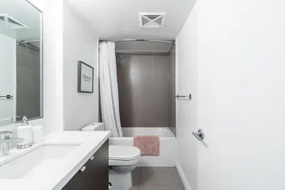 a white bathroom with a sink and a toilet and a tub at Yorkville Plaza Express Stay in Toronto