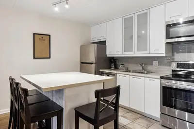 a kitchen with white cabinets and a counter with chairs at Whispering Pines Escape in Collingwood