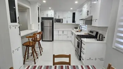 a white kitchen with white appliances and wooden stools at Home in Niagara region in St. Catharines