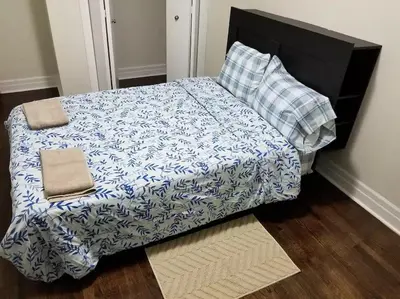 a bed with a blue and white comforter and pillows at Private Rooms, Free Parking, Full Kitchen, Best Prices in Town- York University Heights in Toronto