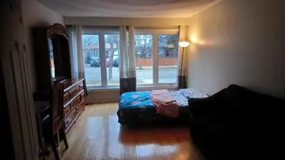 a living room with a bed and a window at Private Rooms, Free Parking, Full Kitchen, Best Prices in Town- York University Heights in Toronto