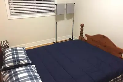 a bedroom with a bed with blue sheets and a window at Private Rooms, Free Parking, Full Kitchen, Best Prices in Town- York University Heights in Toronto