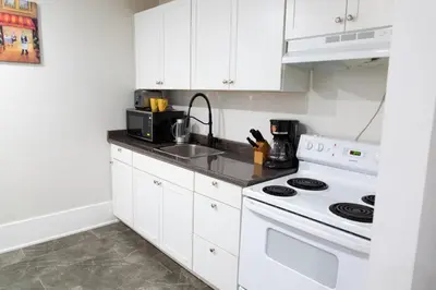 a white kitchen with a stove and a sink at Downtown Apartment 6-7 people in Bowmanville