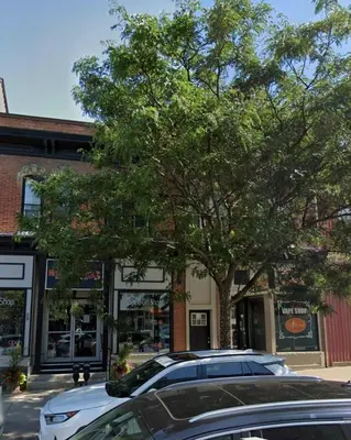 two cars parked in front of a building with a tree at Downtown Apartment 6-7 people in Bowmanville