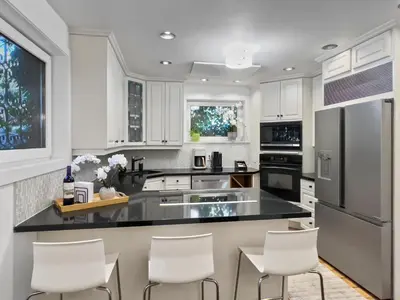 a kitchen with white cabinets and a black counter top at Hot Tub Haven in Toronto