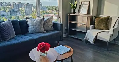 a living room with a blue couch and a table at Elegant 2BR & 2BA Retreat in Prime Yorkville, Downtown in Toronto