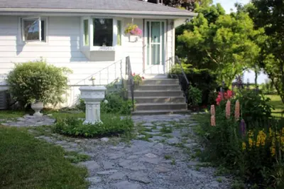 a house with a stone walkway in front of it at Cute and Cozy Lakefront Cottage in Wellington