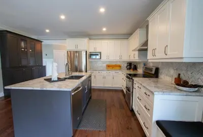 a kitchen with white cabinets and granite counter tops at Deer Run Cottage- Golf Course cottage in Kawartha Lakes