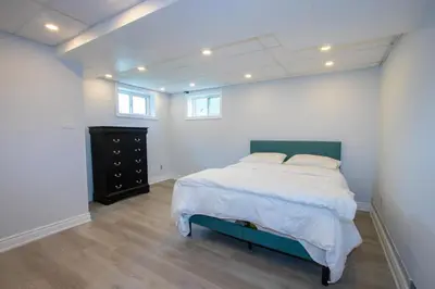 a bedroom with a large bed and a black dresser at Deer Run Cottage- Golf Course cottage in Kawartha Lakes