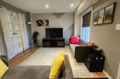a living room with a couch and a flat screen tv at Moons & Noons -Separate Unit for your Comfort in Ajax