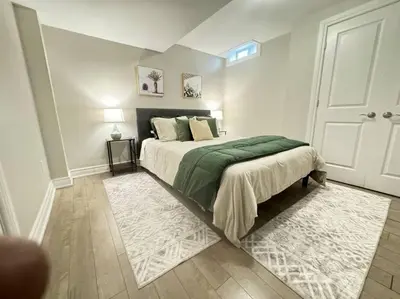 a bedroom with a bed with a green blanket and a door at Cosy Guest Suite Near Shops, Transit, Hwy and GO! in Mississauga