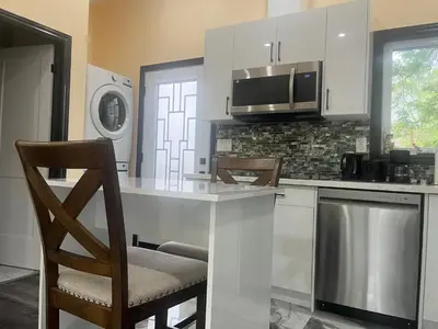 a kitchen with a counter with chairs and a microwave at The Grassy Oasis in Brampton