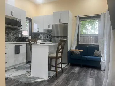 a kitchen with white cabinets and a blue couch at The Grassy Oasis in Brampton