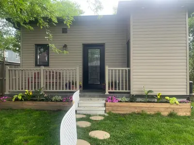 a house with a front porch with flowers in the yard at The Grassy Oasis in Brampton