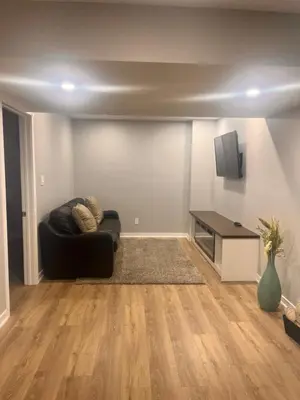 a living room with a black couch and a table at Bowmanville basement apartment in Bowmanville