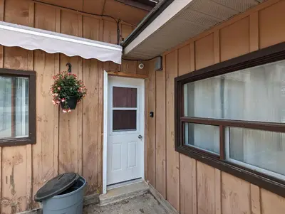 a house with a door and a window and a trash can at Modern Tiny Wood Cottage 0 in Wasaga Beach