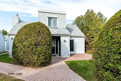 a white house with two large hedges in front of it at Mountain View Villas One Bed Loft Suite in Collingwood