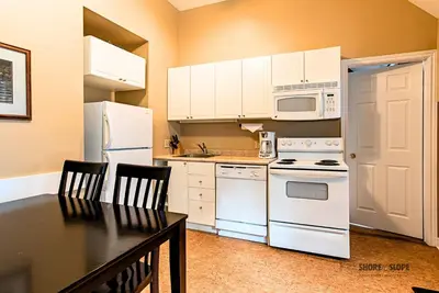 a kitchen with white appliances and a table with chairs at Mountain View Villas One Bedroom Suite in Collingwood