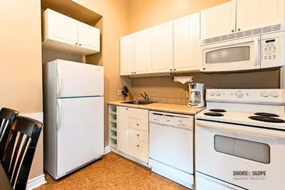 a kitchen with white appliances and white cabinets at Mountain View Villas One Bedroom Suite in Collingwood