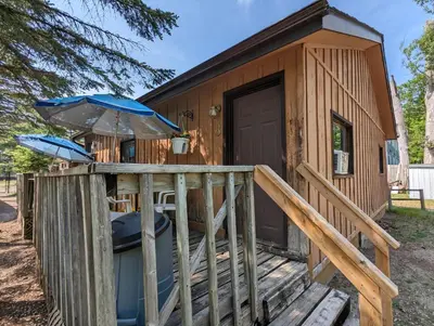 a cabin with a deck and an umbrella at Tiny Wood Cottage 08 in Wasaga Beach