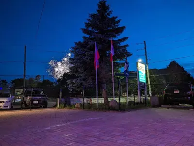 a parking lot with flags and a tree at night at Tiny Wood Cottage 08 in Wasaga Beach