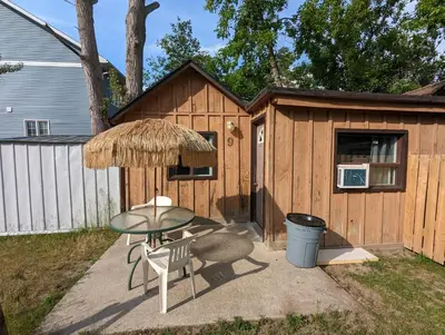 a patio with a table and chairs and a building at Tiny Wood Cottage 09 in Wasaga Beach