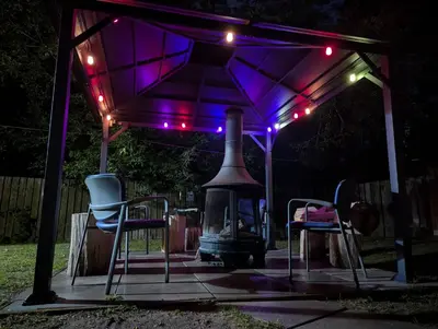 a gazebo with two chairs and a grill with lights at Tiny Wood Cottage 09 in Wasaga Beach