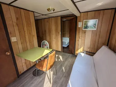 a small room with a bed and a desk and a table at Tiny Wood Cottage 09 in Wasaga Beach