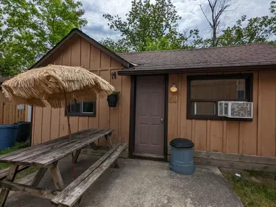 a wooden cabin with a bench and an umbrella at Tiny Wood Cottage 10 in Wasaga Beach