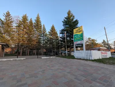a sign in a parking lot next to a fence at Tiny Wood Cottage 10 in Wasaga Beach