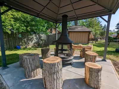 a group of logs and a grill under a tent at Tiny Wood Cottage 12 in Wasaga Beach