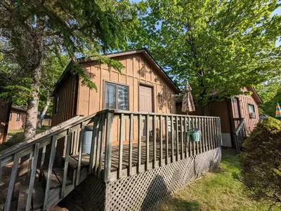 a wooden house with a porch and a fence at Tiny Wood Cottage 14 in Wasaga Beach