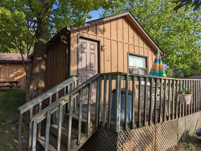 a tiny house with a porch and a deck at Tiny Wood Cottage 15 in Wasaga Beach