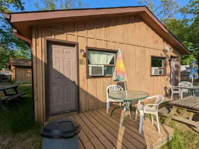 a small cabin with a table and chairs on a deck at Tiny Wood Cottage 16 in Wasaga Beach