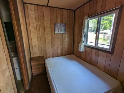 a small bed in a room with a window at Tiny Wood Cottage 17 in Wasaga Beach