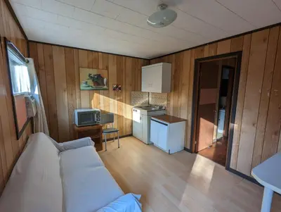 a living room with a couch and a kitchen at Tiny Wood Cottage 20 in Wasaga Beach