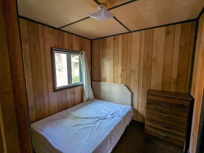 a small bedroom with a bed and a window at Tiny Wood Cottage 21 in Wasaga Beach