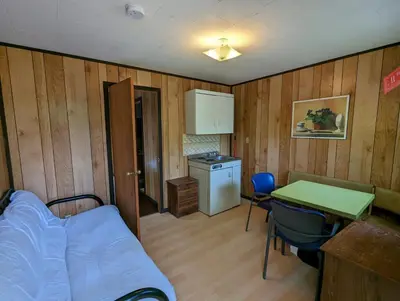 a room with a bed and a table and a kitchen at Tiny Wood Cottage 22 in Wasaga Beach