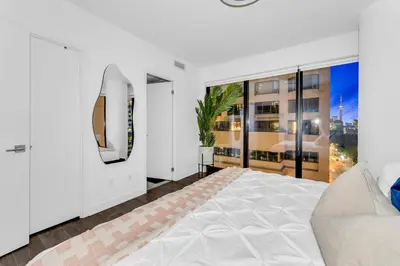 a white bedroom with a bed and a large window at The Royal 2 Bedroom Condo Yorkville in Toronto