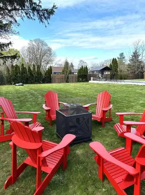a group of red chairs and a television in a field at Alba Cottage with Brand New Pool in Queenston
