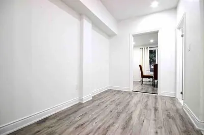 an empty living room with white walls and wood floors at Modern Luxury Home next to Tim Hortons Field in Hamilton