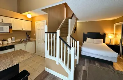 a bedroom with a bed and a kitchen with a staircase at Mountain Loft Suite with Pool and Hot Tub in Blue Mountains