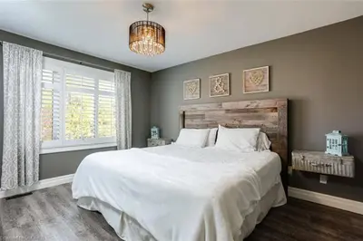 a bedroom with a large white bed and a chandelier at The Family Escape Townhome in Collingwood