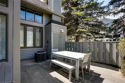 a patio with a white table and chairs in front of a house at The Family Escape Townhome in Collingwood