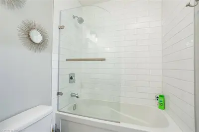 a white bathroom with a tub and a mirror at The Family Escape Townhome in Collingwood